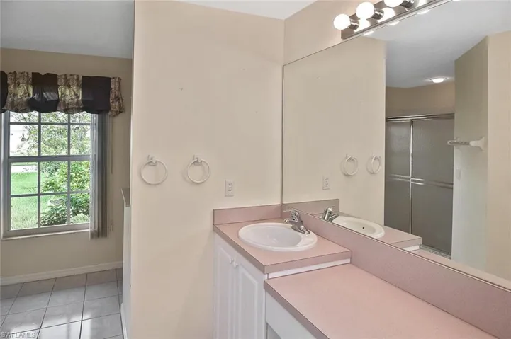 Bathroom with vanity, light tile patterned floors, and a stall shower
