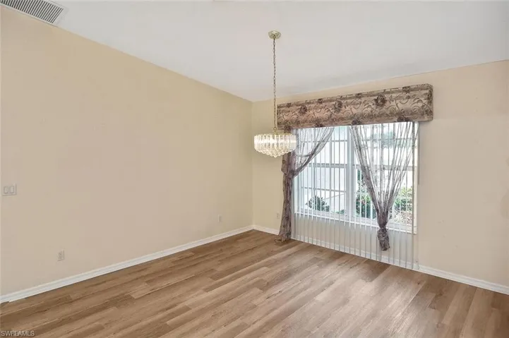 Unfurnished dining area featuring wood finished floors and a chandelier