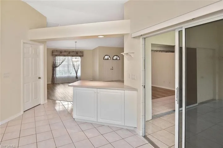 Kitchen with light tile patterned flooring, white cabinets, light countertops, a peninsula, and pendant lighting