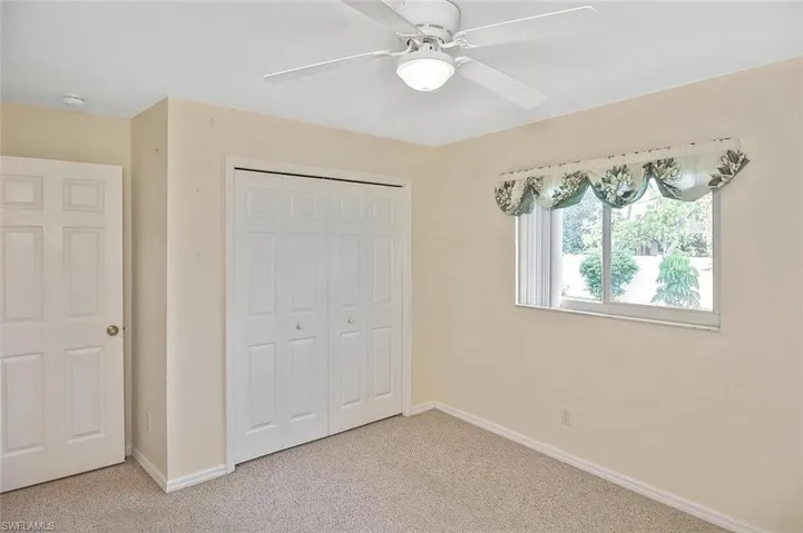 Unfurnished bedroom with light carpet, a closet, and a ceiling fan