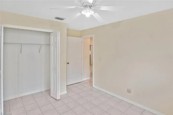 Unfurnished bedroom featuring a closet, light tile patterned floors, and a ceiling fan
