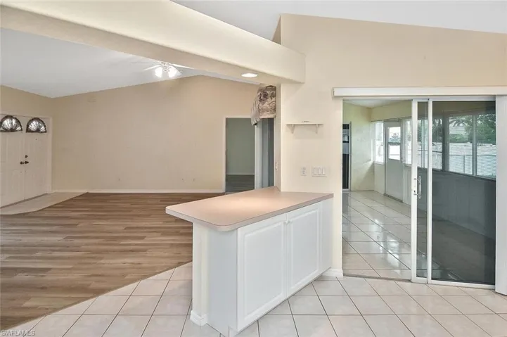 Kitchen featuring light tile patterned floors, open floor plan, vaulted ceiling, light countertops, and a ceiling fan
