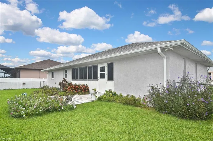Back of house featuring stucco siding, a shingled roof, and a sunroom