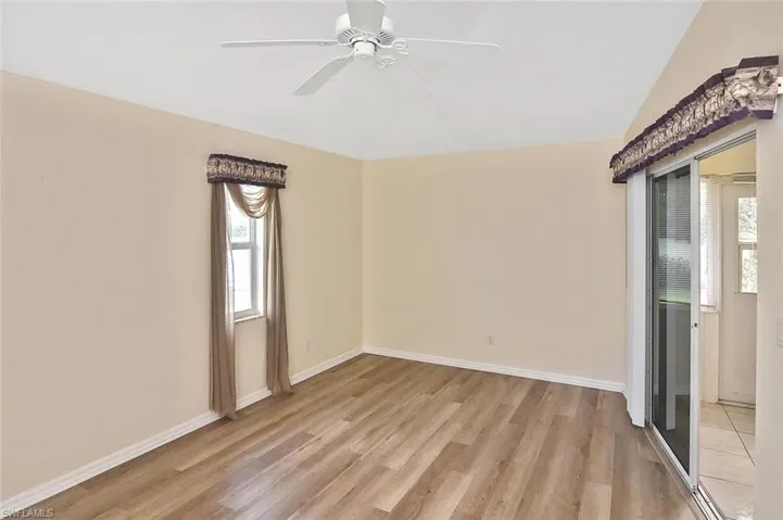 Empty room with light wood finished floors, a ceiling fan, and vaulted ceiling