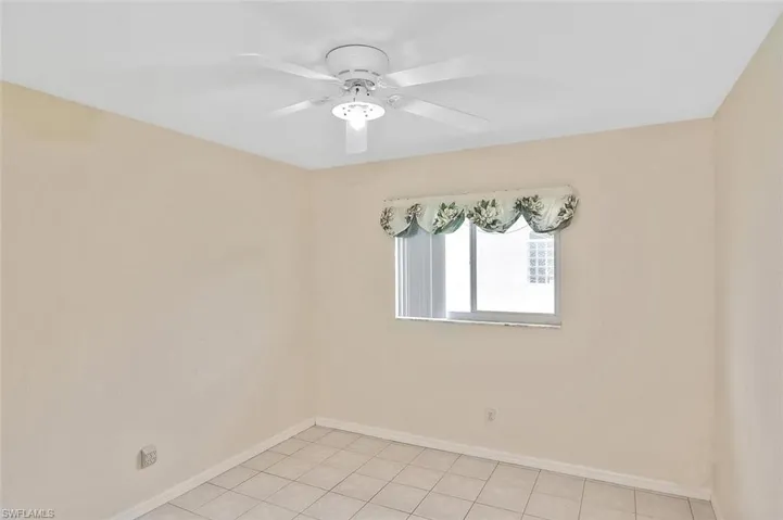 Empty room with light tile patterned floors and ceiling fan