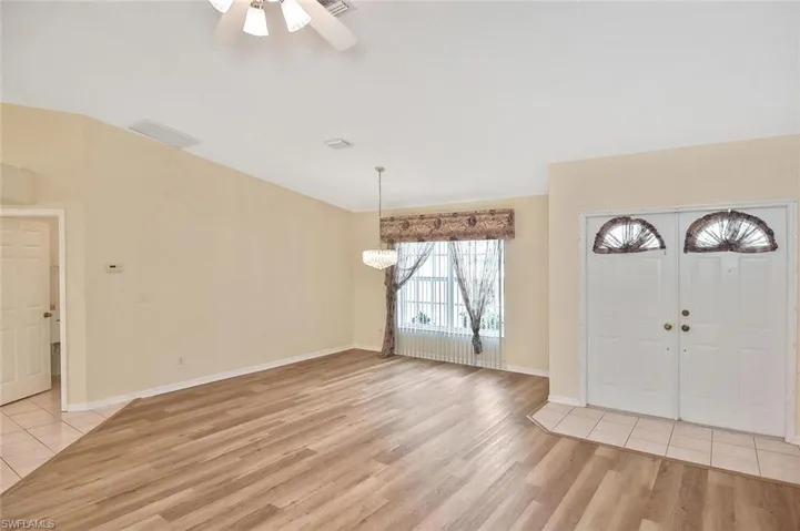 Foyer with light wood finished floors, a ceiling fan, and a chandelier