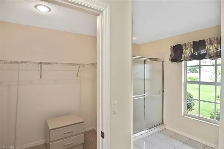Full bath featuring light tile patterned floors, a shower stall, and a walk in closet
