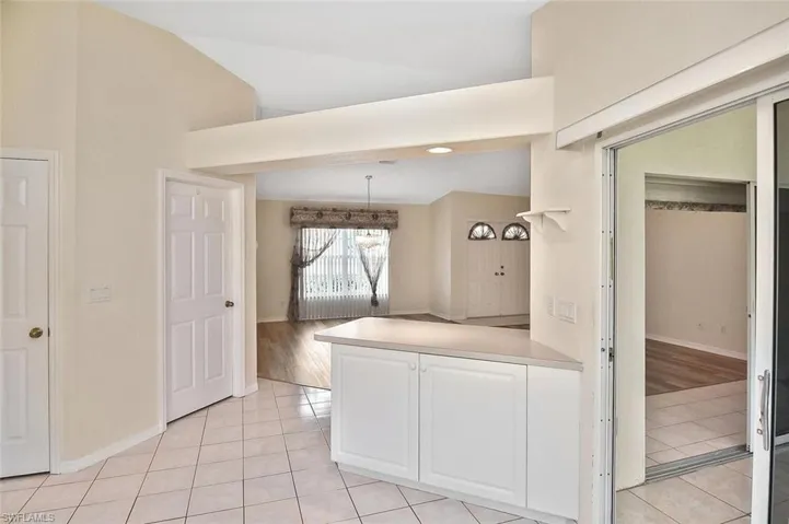 Kitchen featuring light tile patterned floors, a peninsula, white cabinetry, light countertops, and hanging light fixtures