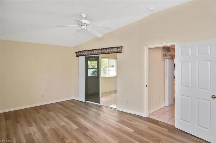 Empty room with vaulted ceiling, light wood-type flooring, and ceiling fan
