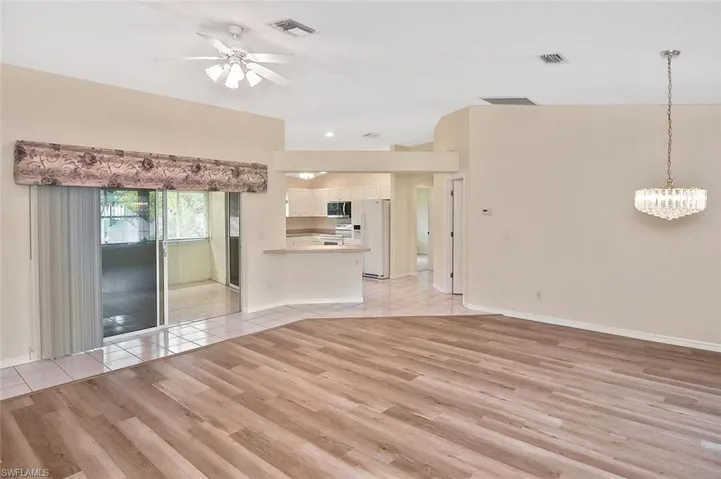 Unfurnished living room featuring light wood-style floors, ceiling fan, and a chandelier