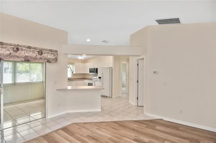 Kitchen with light tile patterned floors, white appliances, light countertops, white cabinetry, and a peninsula