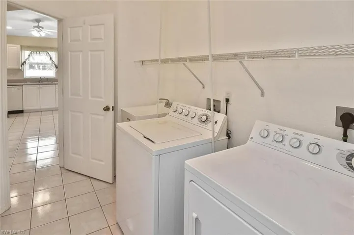Laundry room with light tile patterned floors, washing machine and dryer, and a ceiling fan