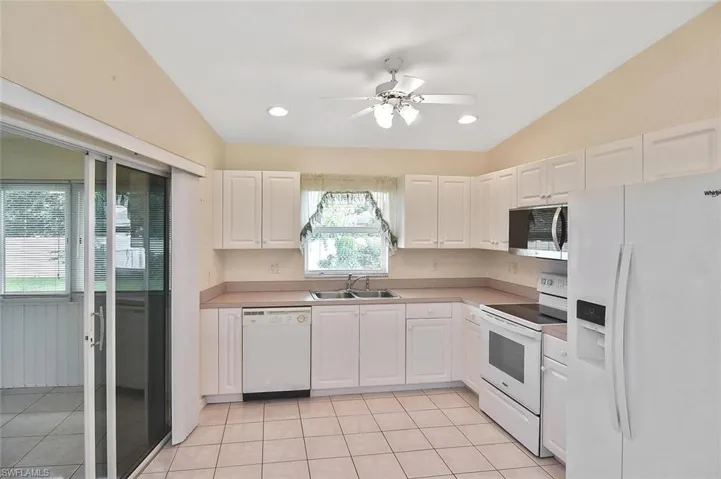 Kitchen with white appliances, light tile patterned floors, white cabinetry, light countertops, and recessed lighting