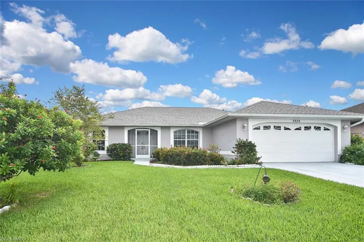 Single story home with stucco siding, an attached garage, driveway, and a front lawn