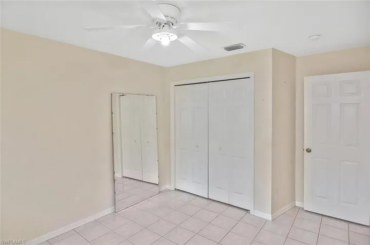 Unfurnished bedroom featuring a closet, light tile patterned floors, and ceiling fan