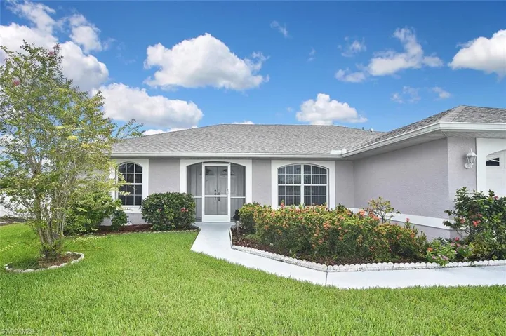 View of front of house with stucco siding, a garage, a front lawn, and a shingled roof