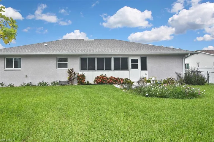 Back of property featuring a shingled roof, stucco siding, and a sunroom