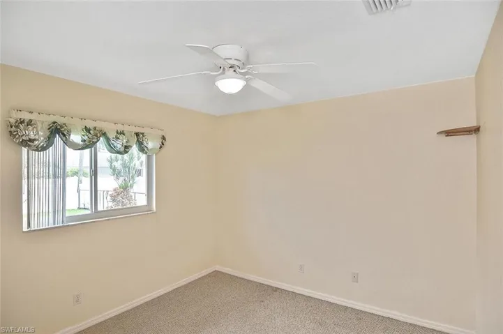 Carpeted spare room featuring baseboards and a ceiling fan