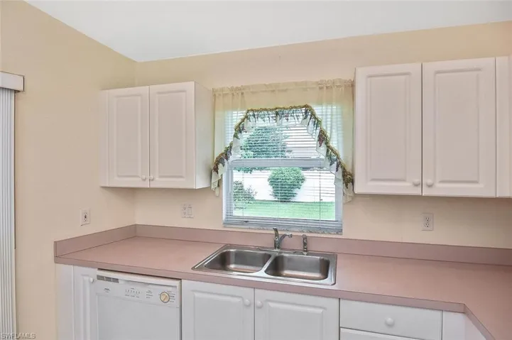 Kitchen with white cabinets, dishwasher, and light countertops