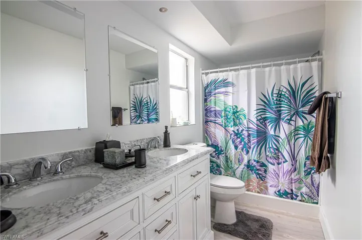 Bathroom featuring double vanity, curtained shower, and light wood-type flooring