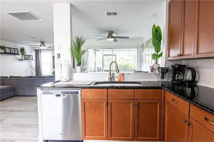 Kitchen featuring open floor plan, dishwasher, a ceiling fan, and wood finish cabinets