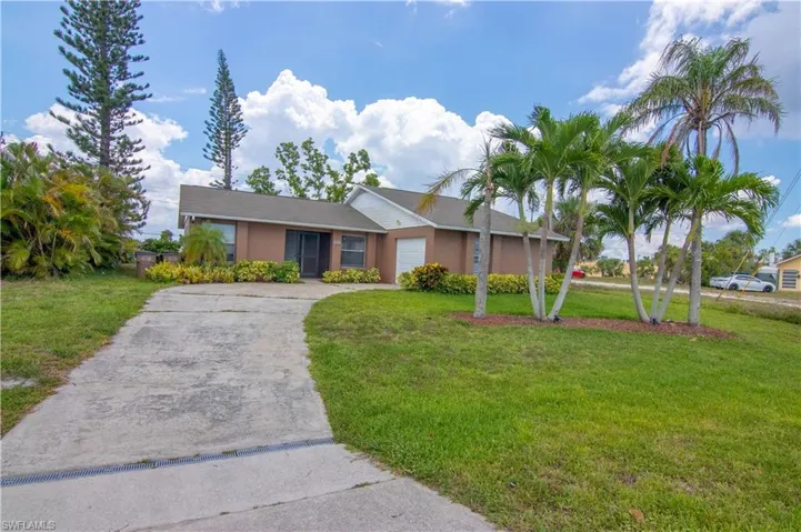 Ranch-style house featuring a front lawn, a garage, and concrete driveway