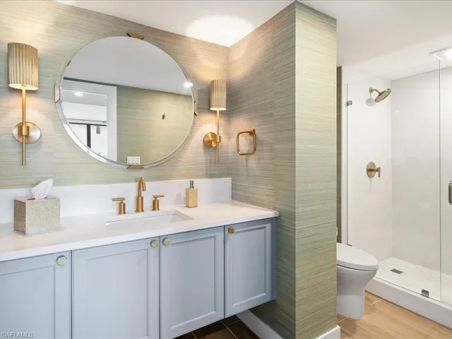 Bathroom with vanity, wood finish floors, tile walls, and a stall shower