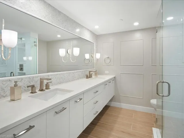 Full bathroom with a shower stall, double vanity, wood tiled floors, tasteful backsplash, and recessed lighting