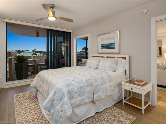 Bedroom featuring wood finished floors, multiple windows, access to exterior, and a ceiling fan