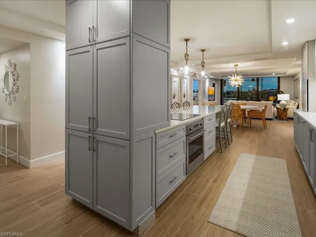 Kitchen featuring gray cabinetry, wood tiled floors, recessed lighting, a kitchen bar, and hanging light fixtures