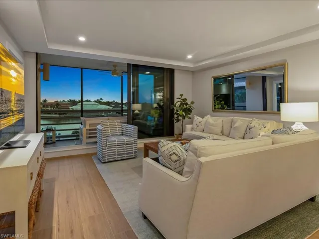 Living room with a tray ceiling, light wood finished floors, and recessed lighting