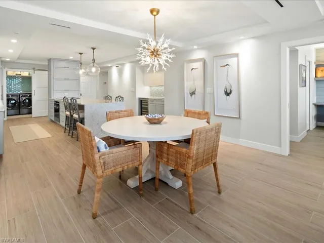 Dining area with wood finish floors, a raised ceiling, recessed lighting, washing machine and clothes dryer, and a chandelier