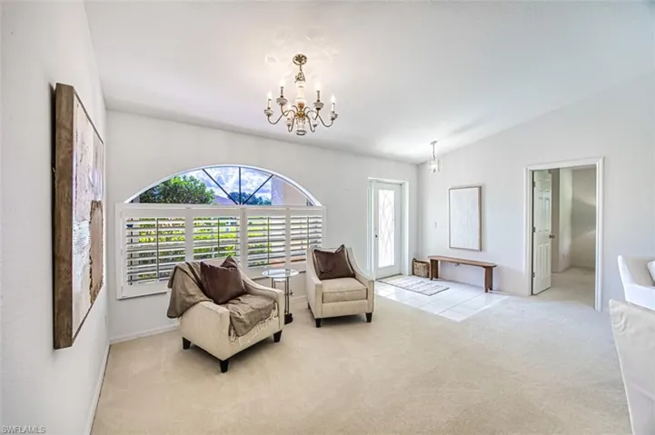 Sitting room featuring carpet flooring, vaulted ceiling, and an inviting chandelier
