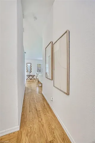 Hall with light hardwood / wood-style flooring and lofted ceiling