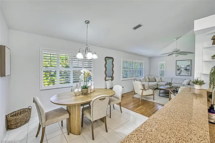 Dining space featuring light tile patterned flooring and ceiling fan with notable chandelier