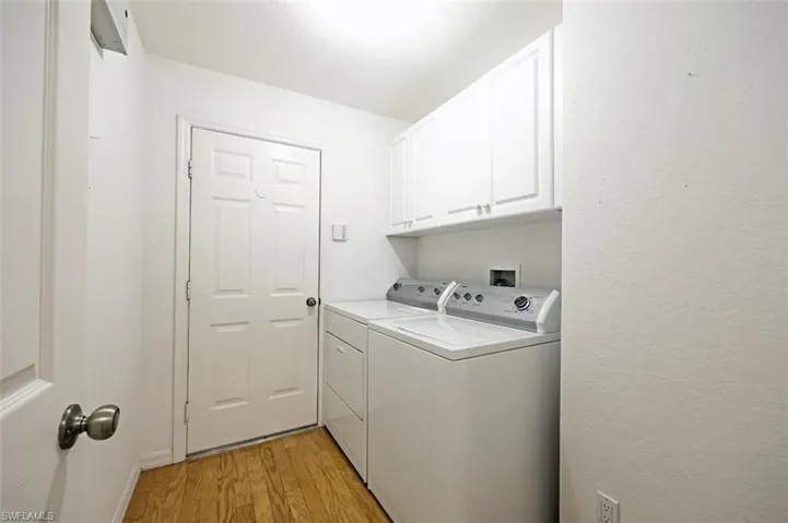 Laundry area featuring separate washer and dryer, light hardwood / wood-style flooring, and cabinets