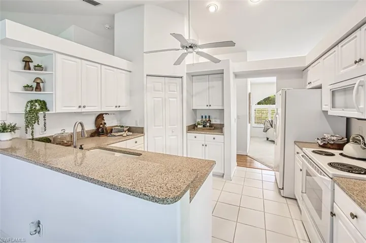 Kitchen featuring light wood-type flooring, ceiling fan, white appliances, and white cabinets