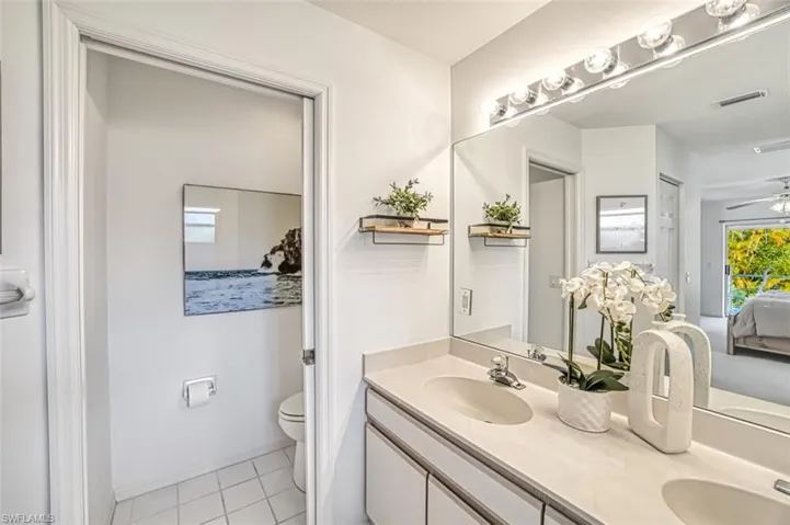 Bathroom featuring ceiling fan, toilet, double sink vanity, and tile patterned flooring