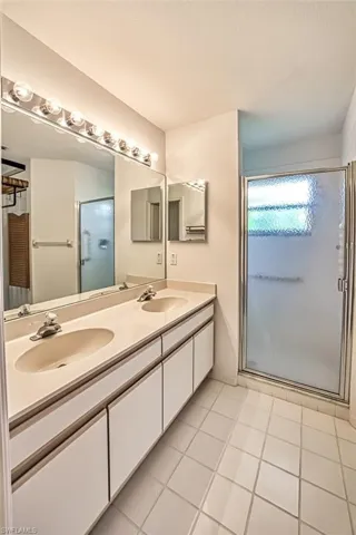 Bathroom featuring walk in shower, tile patterned floors, and dual bowl vanity