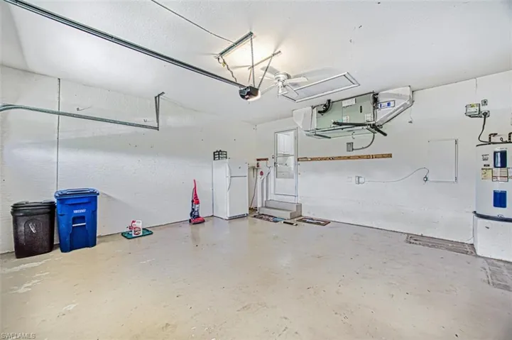 Garage featuring a garage door opener, white fridge, and water heater