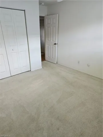 Unfurnished bedroom with light carpet and a closet