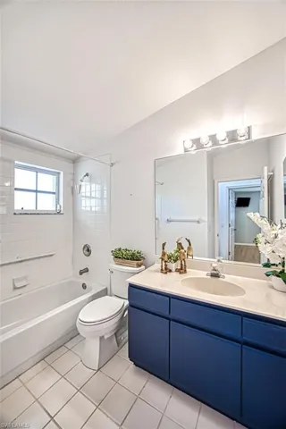 Full bathroom with tiled shower / bath combo, vanity, tile patterned flooring, and toilet