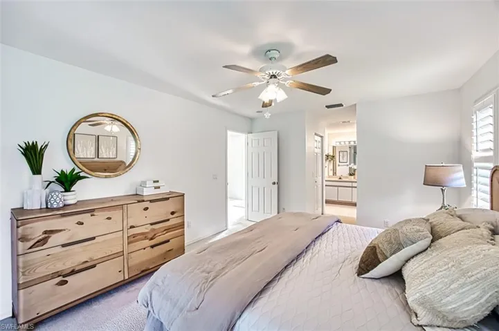 Carpeted bedroom with ensuite bath and ceiling fan