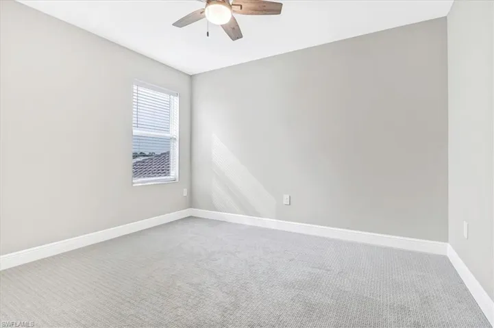 Empty room with light colored carpet and a ceiling fan