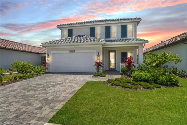 Mediterranean / spanish-style house with a tile roof, decorative driveway, an attached garage, and covered porch
