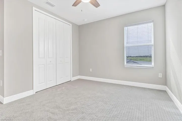 Unfurnished bedroom with light colored carpet, a closet, and ceiling fan