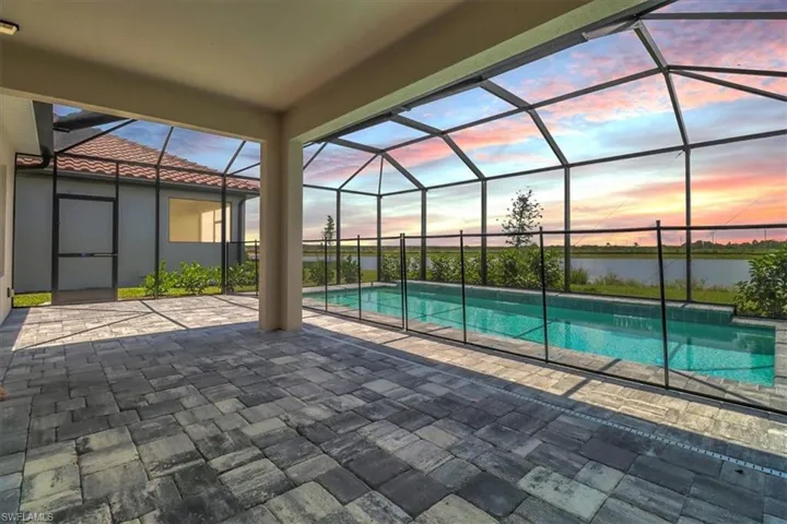 Pool at dusk featuring a sunroom, a patio, glass enclosure, and an outdoor pool