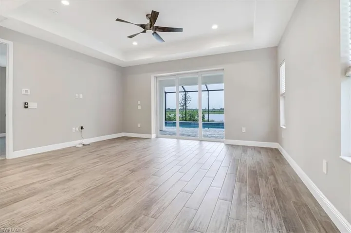 Unfurnished room featuring a ceiling fan, a raised ceiling, light wood-style flooring, and recessed lighting