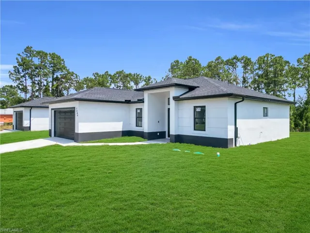 Prairie-style home with stucco siding, a front lawn, an attached garage, concrete driveway, and a shingled roof
