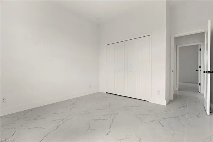 Unfurnished bedroom with light marble finish floors, baseboards, and a closet